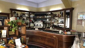 Un espace bar avec des étagères en bois remplies de bouteilles, un appareil à café et une caisse enregistreuse.