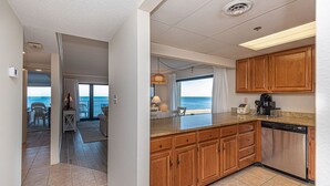 A kitchen with wooden cabinets, a dishwasher, and a view of the ocean.