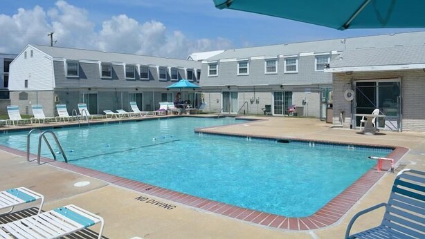 A swimming pool area with lounge chairs and umbrellas. - Quaint, spacious 2 bedroom townhouse with free WiFi and an outdoor pool located downtown on the bayside and only three blocks to the beach! (Ocean City)