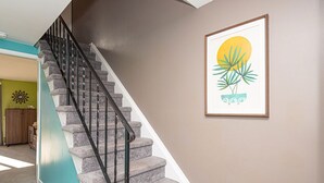 A staircase with a black handrail and stone steps, leading to a room with teal walls and a wooden cabinet. - Quaint, spacious 2 bedroom townhouse with free WiFi and an outdoor pool located downtown on the bayside and only three blocks to the beach! (Ocean City)