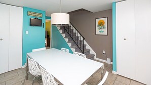 A modern kitchen with a white table and chairs, a built-in stove, and a staircase leading to another level. - Quaint, spacious 2 bedroom townhouse with free WiFi and an outdoor pool located downtown on the bayside and only three blocks to the beach! (Ocean City)