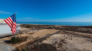 A beach area with a flag, sandy terrain, and a clear view of the ocean.