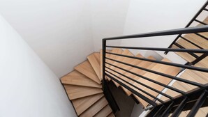 Eine Wendeltreppe mit hölzernen Stufen und einem schwarzen Metallgeländer.