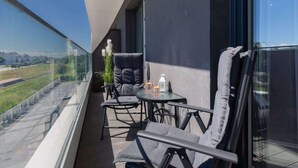 Ein Balkon mit Blick auf eine Stadtlandschaft, ein Tisch mit Stühlen und ein Blumentopf.