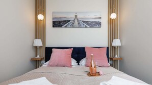 Ein Hotelzimmer mit einem Bett, zwei Nachttischlampen, einem Bild an der Wand und einer Flasche auf dem Bett.