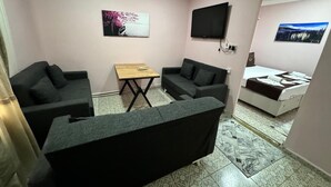 Un espacio habitable compacto con sofá, una mesita, televisión y cama.