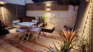 A patio with a table and chairs, a potted plant, and a brick wall.