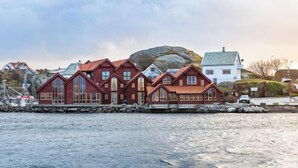 A coastal building with a prominent rock formation in the background. - Sirevåg Hotel (Ha)