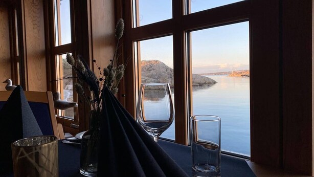 A table with a clear glass, a vase with dried plants, and a duck figurine. - Sirevåg Hotel (Ha)
