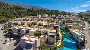 Un quartier résidentiel avec des immeubles modernes, une piscine centrale et un paysage montagneux en arrière-plan.
