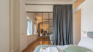 Ein Hotelzimmer mit Bett, Schreibtisch, Stuhl und Blick auf den Flur.