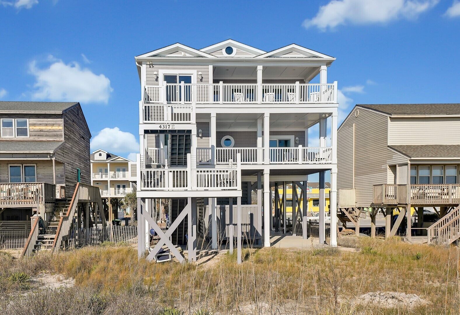 A multi-story beachfront building with balconies and a sandy beach in the foreground.