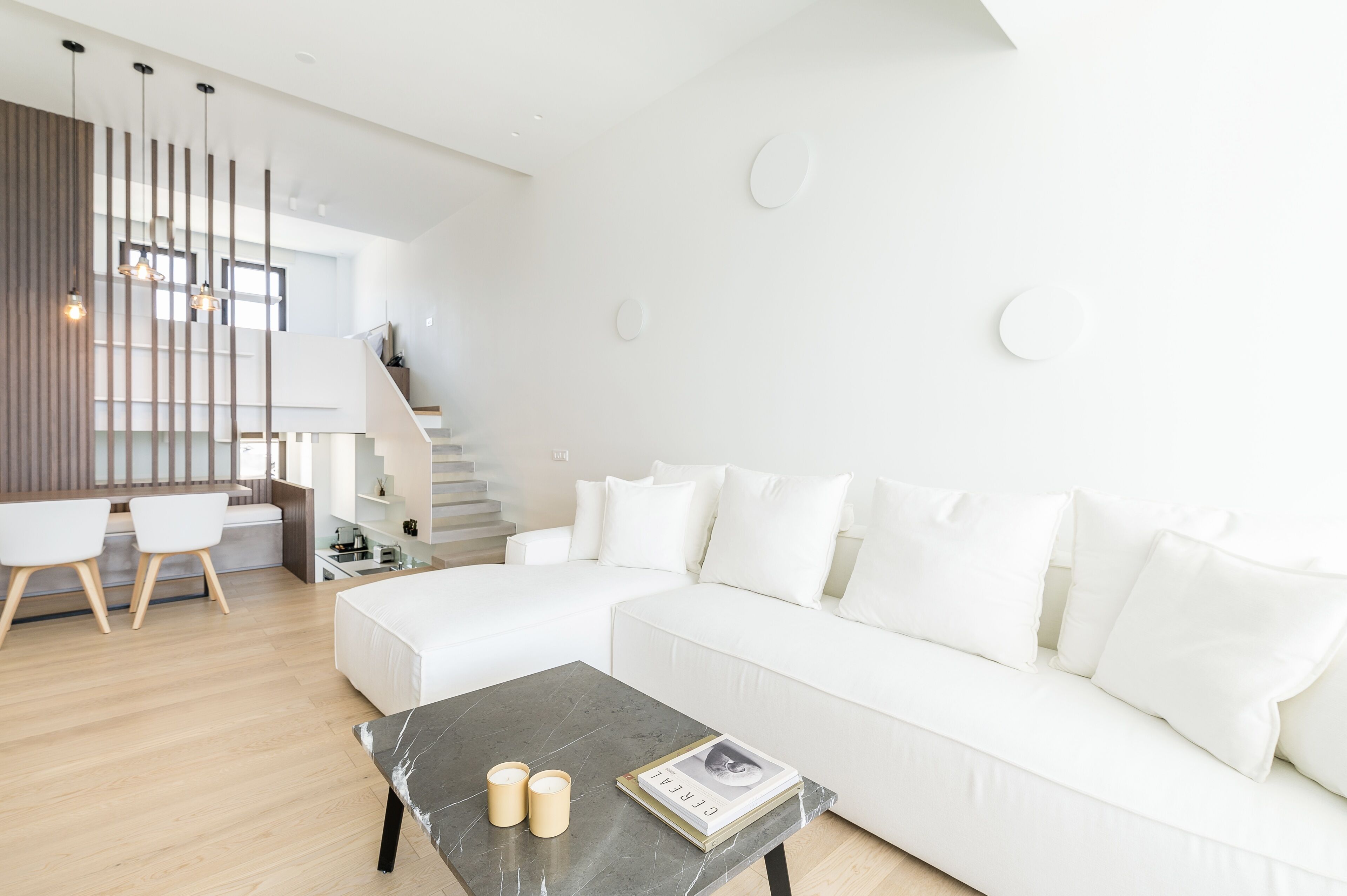 A modern living room with a white sectional sofa, a marble coffee table, and a staircase leading to an upper level.