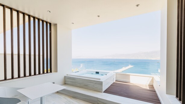 A balcony with a hot tub, white furniture, and a view of the sea. - GM Luxury Suites & Spa (Sitia)