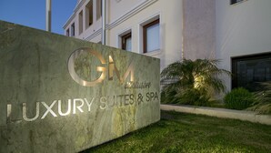 A sign for "GM Luxury Suites & SPA" with a modern building in the background. - GM Luxury Suites & Spa (Sitia)