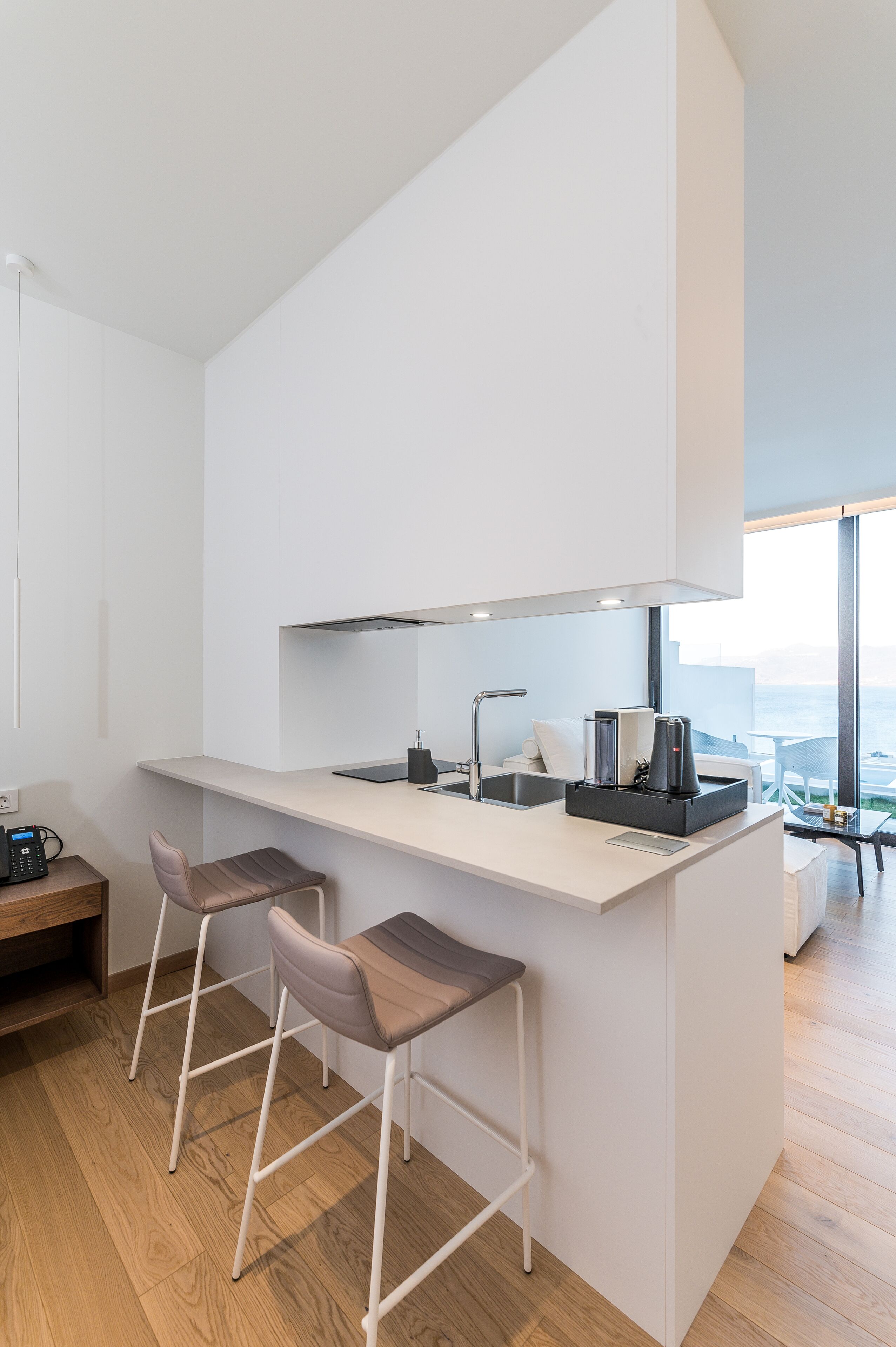 Uma cozinha moderna com uma ilha central, banquetas e vista para o mar.
