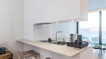Uma cozinha moderna com uma ilha central, banquetas e vista para o mar.