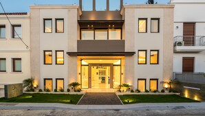 A modern two-story building with a central entrance, large windows, and a well-lit facade. - GM Luxury Suites & Spa (Sitia)