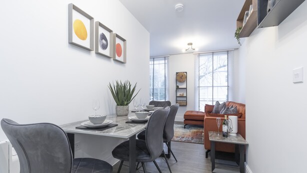 Una sala de estar moderna con comedor, que incluye un sofá, una mesa de centro y una mesa de comedor con sillas.