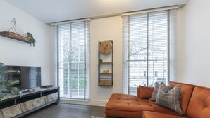 Un salón con sofá, televisor y planta.