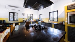 A modern kitchen with a central island, black cabinets, and a yellow backsplash. - Villa Monte Maria Pratas (Setubal)