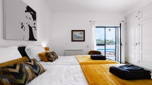A hotel room with a bed, a large window, a door, and a radiator. - Villa Monte Maria Pratas (Setubal)
