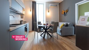 A modern kitchen with grey cabinets, a dining area with a table and chairs, and a grey sofa. - Casa del Monumento del Re by Wonderful Italy (Torino)