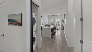 A modern kitchen with a central island, a dining area with bar stools, and a view of the ocean through a large window. - Newly Built Condo w/ 3 Pools & Steps to Beach + Free Attraction Tickets! (Santa Rosa Beach)