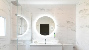 Een moderne badkamer met een douchecabine van glas, een witte wastafel met spiegel en een toilet.