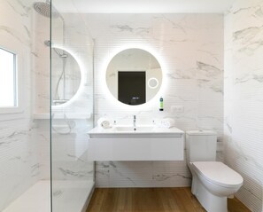 A modern bathroom with a glass-enclosed shower, a white sink with a mirror, and a toilet. - Logis Hotel Thermal (Saubusse)