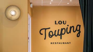 Un mur sur lequel on peut lire l’inscription « LOU TOUPING RESTAURANT », qui indique le nom de l’établissement.