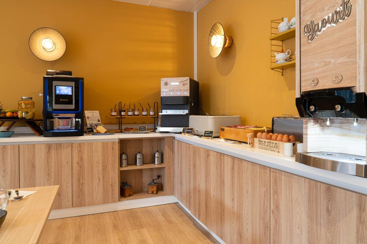 A coffee shop interior with a coffee machine, a display of pastries, and a wooden counter.
