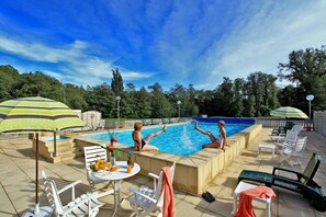 A swimming pool area with lounge chairs, umbrellas, and a table with fruits and drinks. - Logis Hotel Thermal (Saubusse)