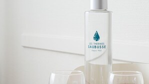 Een glazen fles met een etiket, twee glazen en een brochure op een houten ondergrond.