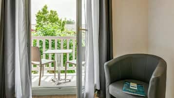 Una habitación con balcón, una silla, una mesa y un libro sobre la silla.