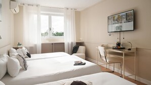 Een hotelkamer met twee bedden, een bureau, een stoel, een televisie en een raam met gordijnen.