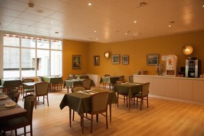 A dining area with tables and chairs, a counter with a coffee machine, and framed pictures on the wall. - Logis Hotel Thermal (Saubusse)