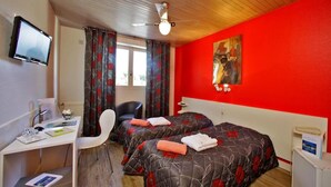 Een hotelkamer met twee bedden, een bureau, een stoel, een televisie en een rode wand.