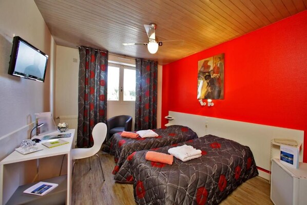 A hotel room with two beds, a desk, a chair, a television, and a red wall. - Logis Hotel Thermal (Saubusse)