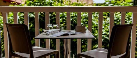 A balcony with two chairs and a table, a laptop, and two salt and pepper shakers.