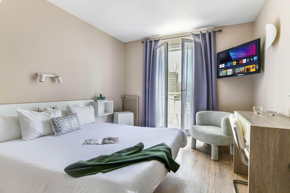 Hotelkamer met een bed, bureau, stoel, televisie en raam met gordijnen.