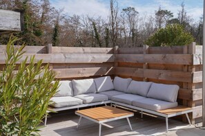 An outdoor seating area with a wooden bench and a white sofa. - Logis Hotel Thermal (Saubusse)