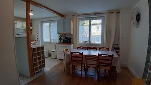 Una cocina compacta con comedor, que incluye una mesa con sillas, un ventanal con cortinas y un radiador.
