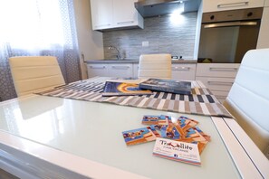 A modern kitchen with white cabinets, a stainless steel oven, and a tiled backsplash.