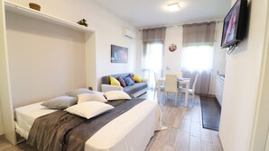 Ein Schlafzimmer mit Bett, einer Couch, einem Fernseher und einem Schreibtisch.