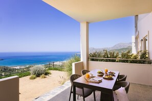 A balcony with a table set for breakfast, overlooking a coastal view. - Villa Stella Suites (Agios Vasileios)