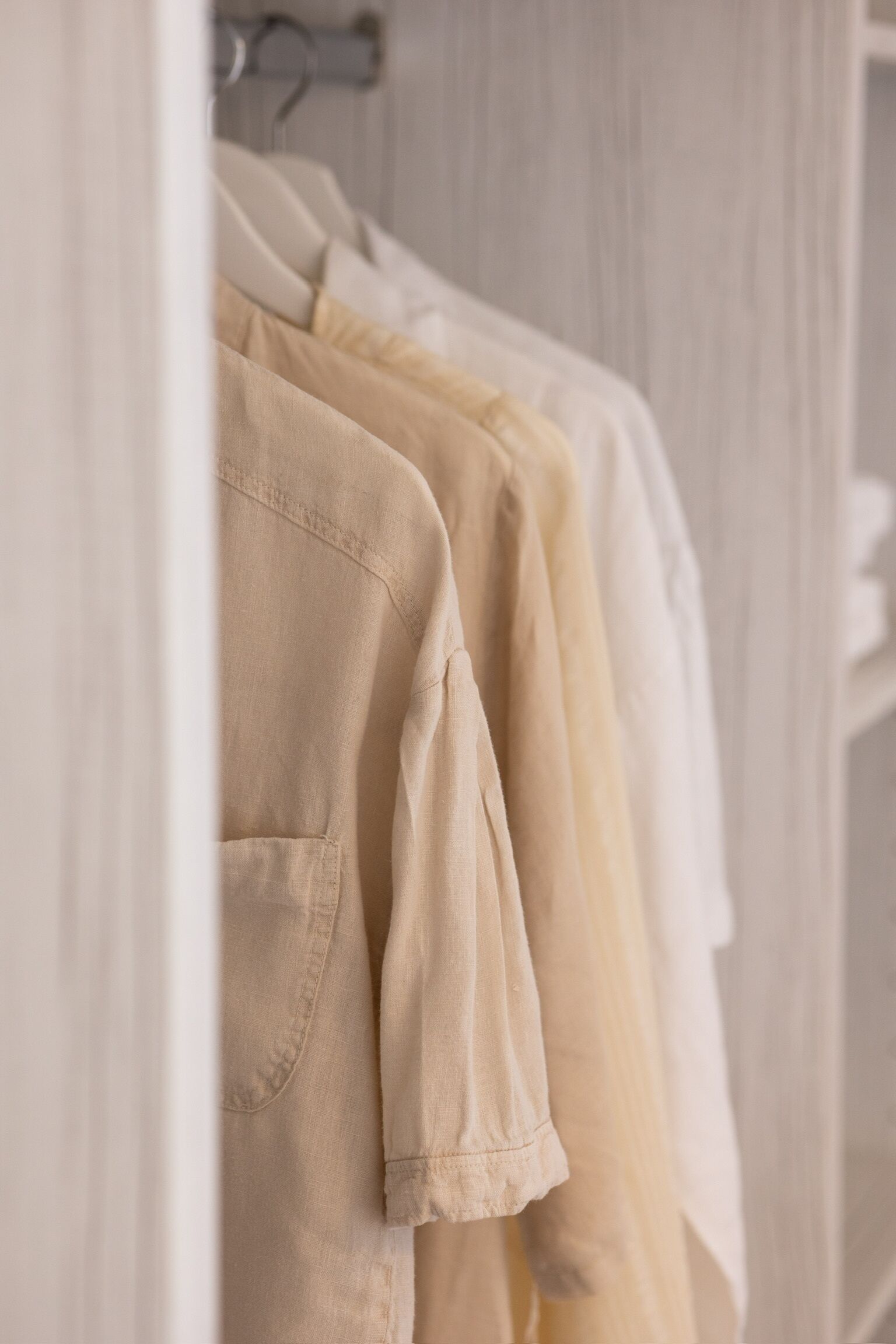 A row of neatly hung shirts in a closet.