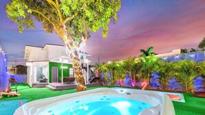 A hot tub in a backyard with a house in the background. - Villa Bonita | 6BR | Pool + Hot Tub (Miami)