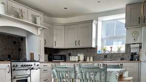 Una cocina moderna con armarios blancos, piso de madera y un comedor con dos sillas.