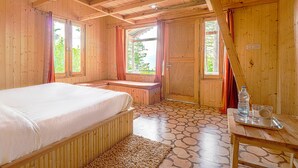 Una cabaña de madera con una cama, un banco y una mesa con una botella y vasos.